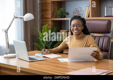 Donna con dreadlock lavora come freelance dall'ufficio domestico Foto Stock