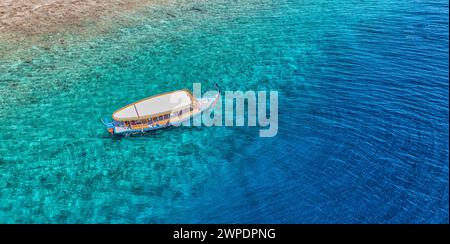 Spiaggia e laguna cristallina con barca bianca. Vista dall'alto dello sfondo dell'acqua turchese. Il mare estivo dall'aria. Vista dall'alto dal drone. Vacanze estive Foto Stock