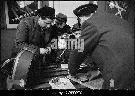 Fotografia che mostra il funzionario doganale che informa i viaggiatori durante il controllo dei passaporti e dei bagagli presso la stazione estera dell'aeroporto di Varsavia nel 1959, parte della serie di fotogiornalismo "Please Open!" Di Wiesław Prażuch. Foto Stock