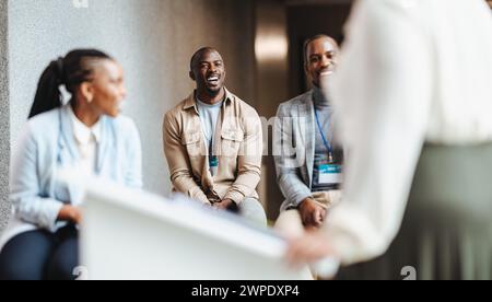 Tre professionisti sorridenti e impegnati in una conversazione informale con l'altoparlante. Gli uomini d'affari trasmettono un senso di lavoro di squadra, networking e positiv Foto Stock