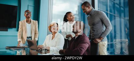 I professionisti aziendali collaborano in un ufficio moderno, utilizzando la tecnologia e lavorando insieme. Con i sorrisi in faccia, hanno un meeti di successo Foto Stock