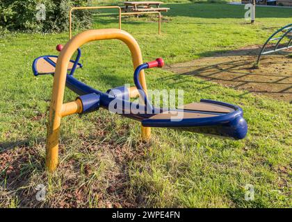 Un'altalena colorata vuota per bambini si trova in un parco giochi all'aperto con erba. Foto Stock