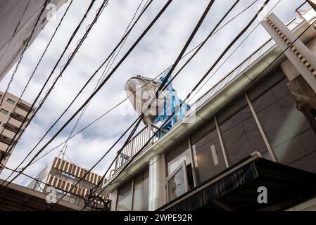 Tokyo - Giappone - circa novembre 2018. Veduta di una strada al mercato del pesce di Tsukiji con cavi d'aria tipici e una grande figura di pesce pubblicizzato Foto Stock