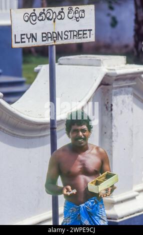 Sri Lanka, Galle; l'uomo mostra vecchie monete olandesi VOC di fronte a una casa in stile coloniale. Il nome della strada ricorda il periodo coloniale olandese. Foto Stock