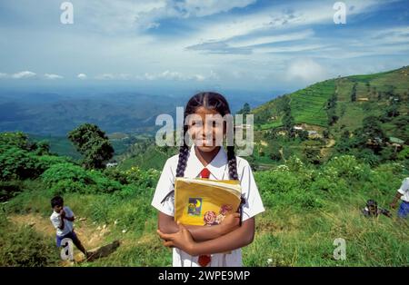 Sri Lanka, studentessa che tiene un libro di testo mentre torna a casa da scuola. Foto Stock