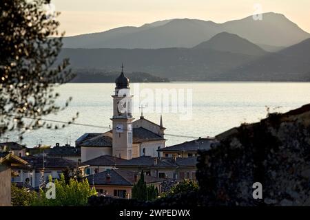 Il paese di Torri del Benaco con la chiesa di San Pietro e Paolo. Sullo sfondo del Lago di Garda. Veneto, Italia. Foto Stock