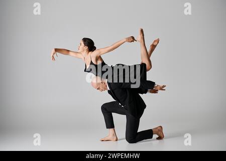 Danza graziosa, giovane coppia che esegue una routine acrobatica in studio con sfondo grigio Foto Stock