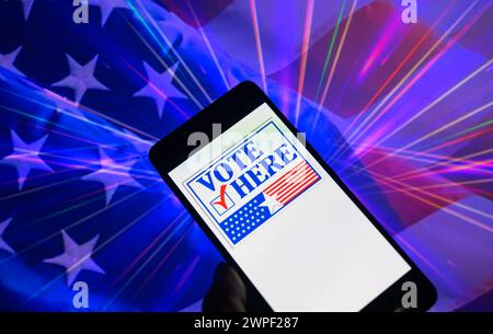 Bruxelles, Belgio. 5 marzo 2024. L'icona Vota qui visualizzata su uno smartphone con la bandiera USA visibile sullo sfondo in questa immagine. Presa a Bruxelles, Belgio. Il 5 marzo 2024. (Foto di Jonathan RAA/Sipa USA) credito: SIPA USA/Alamy Live News Foto Stock