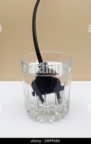 Spina elettrica in un bicchiere di acqua Foto Stock