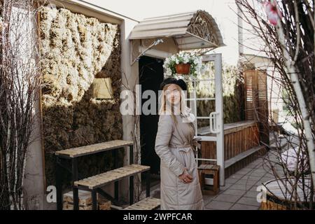 Una figura femminile vestita con un lungo cappotto si erge con sicurezza di fronte a un edificio torreggiante. Foto Stock