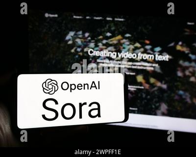 Persona che possiede uno smartphone con il logo del software modello testo-video Sora (OpenAI) davanti al sito web. Mettere a fuoco il display del telefono. Foto Stock