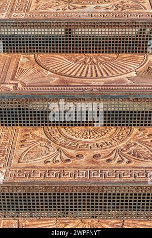 Antichi gradini in ghisa con ornamenti sulla strada della città. Scale in metallo vintage decorate con motivi eleganti all'aperto. Punto di riferimento storico Foto Stock