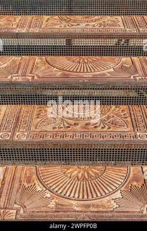 Antichi gradini in ghisa con ornamenti sulla strada della città. Scale in metallo vintage decorate con motivi eleganti all'aperto. Punto di riferimento storico Foto Stock