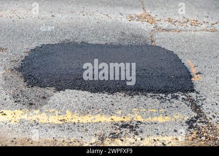 Grande pozzo riparato in una strada a Westcliff on Sea, Essex, Regno Unito, che necessita di una riparazione permanente. Auto parcheggiate con la riparazione di buchi Foto Stock