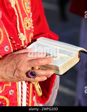 Mano di prete anziano che indossa un grande anello che tiene la Bibbia durante la celebrazione eucaristica Foto Stock