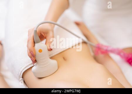 Vista dall'alto ravvicinata della giovane donna irriconoscibile che riceve l'ecografia dal medico. Prevenzione di problemi di gastrite e digestione. Gravidanza ovulazione femminile Foto Stock