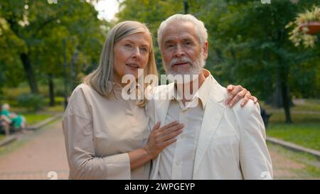 Anziano coppia caucasica amorevole nonni anziani coppia di famiglia fidanzata marito abbracciando la passeggiata di legame fuori dal parco cittadino. Pensionati uomo donna Foto Stock
