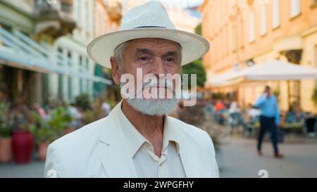 Primo piano calmo vecchio anziano di 60 anni anziano maturo dai capelli grigi caucasico elegante uomo d'affari in pensione intelligente uomo turistico che guarda fuori città Foto Stock