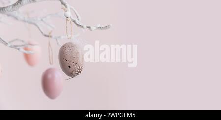 Ramo d'albero decorato con uova di Pasqua su sfondo rosa pastello Foto Stock
