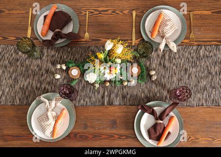 Splendido tavolo per Pasqua decorato con bouquet di carote e fiori nella sala da pranzo Foto Stock