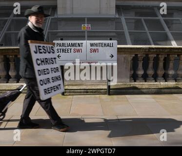 Londra, Regno Unito. 6 marzo 2024. Il cartello di Parliament Street, Whitehall Street, mentre un uomo passeggia con un Gesù Cristo morto per la nostra tavola dei peccati il 6 marzo 2024, Westminster, Londra. Crediti: Paul Marriott/Alamy Live News Foto Stock