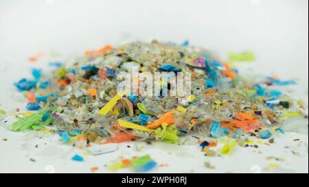 Scatto macro su una pila di microplastiche e sabbia raccolta dalla spiaggia. Concetto di inquinamento microplastico delle acque e riscaldamento globale. Foto Stock