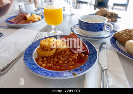 Colazione all'inglese con fagioli al forno, pancetta fritta e succo d'arancia sul tavolo Foto Stock