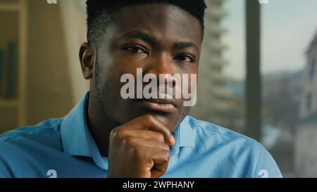Colpo alla testa uomo afroamericano etnico uomo d'affari premuroso pensare tenere la mano sul mento dubitare la sfida decisionale risolvere un'idea di business guardando la fotocamera Foto Stock