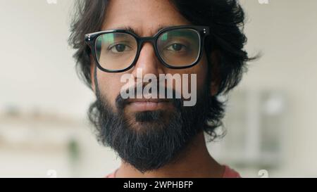 Primo piano uomo arabo musulmano barbuto scapolo proprietario di casa indiano multietnico ragazzo serio guardando la telecamera occhi cattivi visione in occhiali da vista maschio Foto Stock