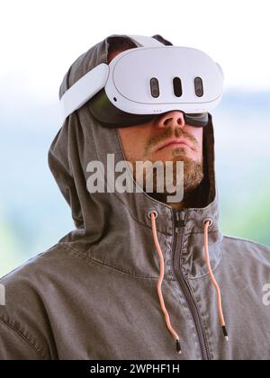 Uomo che indossa una felpa con cappuccio con cuffie per realtà aumentata. Foto Stock