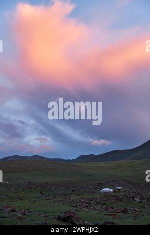 Paesaggio mongolo con steppa di montagna sotto le nuvole di cumuli in corso sul cielo del tramonto, yurts e mandria di capre. Confine naturale di montagna Tsagduult, Wester Foto Stock