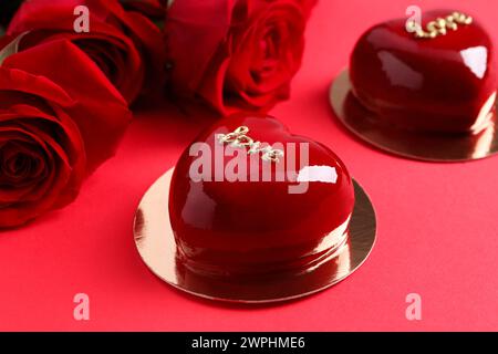 St San Valentino. Deliziose torte a forma di cuore e rose su sfondo rosso, primo piano Foto Stock