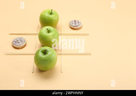 TIC tac di gioco a base di mele e biscotti su sfondo beige Foto Stock