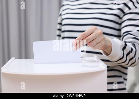 Donna che mette il suo voto nelle urne su sfondo sfocato, primo piano Foto Stock