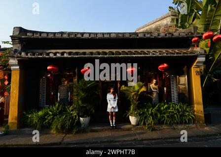 Un turista che posa per una foto di fronte a un vecchio edificio nella città vecchia di Hoi An, Vietnam. Foto Stock