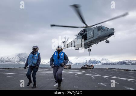 Seaman Caleb Degabriele e Boatswain's Mate di 3a Classe Ali Khadour ritornano da carico agganciato a un elicottero della Marina italiana Foto Stock