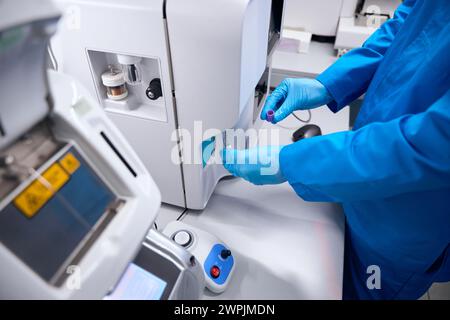 Uomo in uniforme lavora su apparecchi per l'isolamento automatico degli acidi nucleici Foto Stock