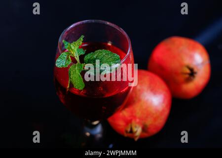 Vista dall'alto del melograno maturo e bicchiere di vino su sfondo nero. Closup estrema Foto Stock