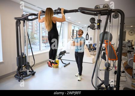 Donna in palestra che fa i pull-up al bar orizzontale Foto Stock