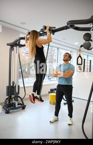 Signora in palestra che fa pull-up sul bar orizzontale Foto Stock