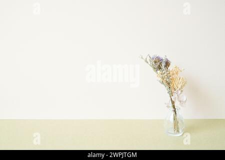 Vaso in vetro di fiori secchi sul tavolo. sfondo bianco avorio Foto Stock