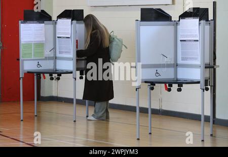 Voto in corso presso la Old St Josephs Gym Hall di Dublino, mentre l'Irlanda tiene referendum sulle modifiche proposte al testo della Costituzione relative alle aree di famiglia e cura. L'emendamento sulla famiglia propone di estendere il significato di famiglia al di là di quello definito dal matrimonio e di includere quelli basati su relazioni "durature”. L'emendamento Care propone di eliminare i riferimenti ai ruoli e ai doveri di una donna in casa e di sostituirlo con un nuovo articolo che riconosce gli assistenti familiari. Data foto: Venerdì 8 marzo 2024. Foto Stock