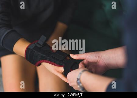 foto ravvicinata di una persona che aiuta una donna ad aggiustare la stecca bifacciale al dito medio. Foto di alta qualità Foto Stock