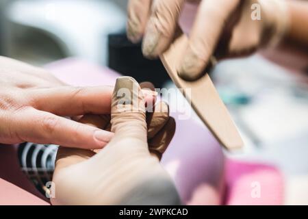 Una manicurista che fa una manicure su una donna nel suo salone delle unghie Foto Stock