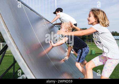 Una ragazza e due fratelli su un halfpipe. Stanno correndo fino al limite Foto Stock