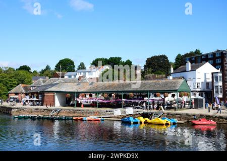 Barche a remi e pedalò ormeggiati sul fiume exe con negozi e ristoranti lungo l'East Quay sul retro, Exeter, Devon, Regno Unito, Europa. Foto Stock