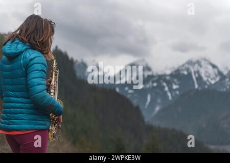 Donna che suona il sassofono in montagna Foto Stock