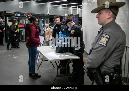 New York, Stati Uniti. 7 marzo 2024. Gli agenti di polizia della Metropolitan Transportation Authority (MTA) perquisiscono la borsa di un pendolare in un checkpoint di sicurezza a Penn Station a New York, negli Stati Uniti, 7 marzo 2024. Lo Stato di New York sta adottando molteplici misure nel tentativo di far fronte ai crimini nel sistema metropolitano di New York City, incluso il dispiegamento di centinaia di membri della Guardia Nazionale. Crediti: Michael Nagle/Xinhua/Alamy Live News Foto Stock