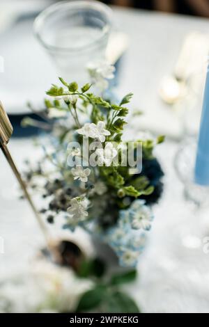 Fiori bianchi artificiali con vegetazione al centro di un tavolo Foto Stock