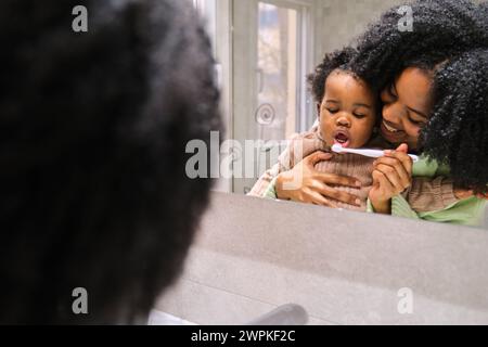 Madre cubana che pulisce i denti della figlia con lo spazzolino. Foto Stock